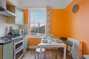 普里茅斯Harbour Court - Free Parking - tucked away on the Barbican - by Ocean City Retreats的厨房拥有橙色的墙壁和白色的桌椅