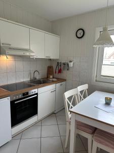 费马恩Albertsdorf Schwalbennest 1的厨房配有白色橱柜、水槽和桌子
