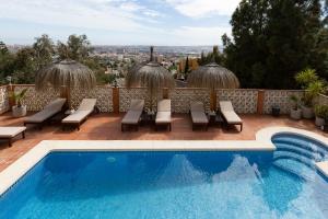 马拉加Bed & Breakfast Villa Botánica的一个带椅子的游泳池,享有城市美景