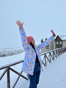 埃尔卡拉法特Edenia Hotel & Nature的站在雪中,手臂在空中的女人