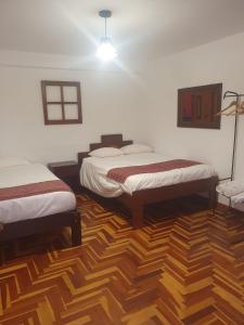 皮萨克shanti pisac的客房设有两张床,铺有木地板。