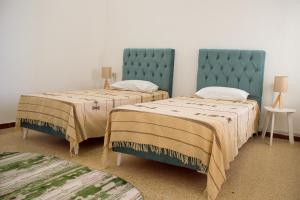 GabèsBEAU SÉJOUR hébergement et spa的客房设有两张带蓝色床头板的床。