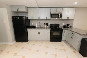 泽西市Mins from NYC Bright & Spacious 4-Bed Unit的厨房配有白色橱柜和黑色冰箱。