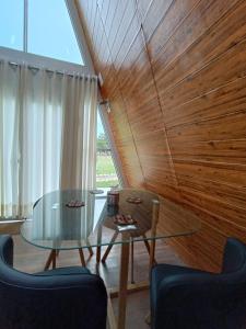 MuyurinaVallecito Lodge的一间设有玻璃桌和木墙的用餐室