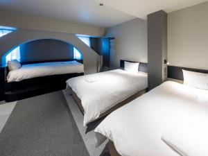 大阪新大阪酒店的卧室配有两张床,中间设有拱门