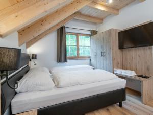 多内尔斯巴赫瓦尔德Villa Petra的一间卧室设有一张配有电视的床和木制天花板。