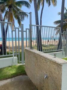圣胡安Beachfront Bliss at Isla Verde的海滩上设有围栏和棕榈树,还有大海