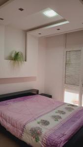 Chott MeriemKalthoum的一间卧室配有一张带紫色毯子的床