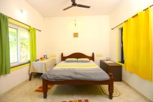 蒂鲁瓦纳马莱Shivalaya Arunachala的一间卧室配有一张带黄色窗帘和桌子的床
