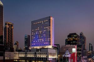 曼谷曼谷拉差阿帕森购物区 MOXY 酒店的一座高大的建筑,上面有蓝色的灯光