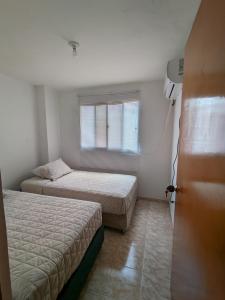 卡塔赫纳Apartamento en Cartagena cerca del aeropuerto的一间卧室设有两张床和窗户。