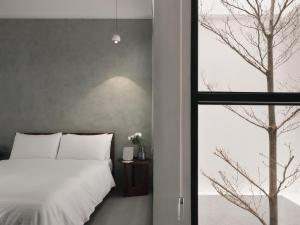 台南廣發寓所的卧室配有白色的床和窗户。