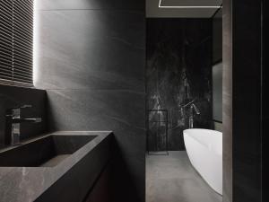 台南廣發寓所的黑色浴室设有水槽和浴缸。
