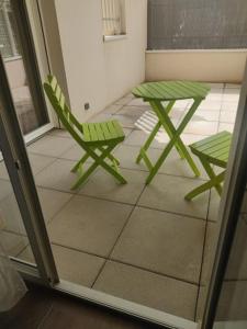 莱斯安格尔斯Cozy studio near Avignon的天井上的绿色椅子和桌子