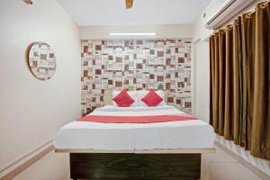 DhantoliOYO Flagship 74330 Hotal Aqsha Paradise的一间卧室配有一张带红色枕头的大床
