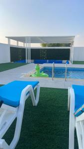 乌姆盖万Falaj Hub Retreat的游泳池旁设有2把蓝色和白色椅子的游泳池
