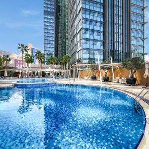 多哈多哈罗塔纳城市中心酒店的一个大型游泳池,其背后是高大的建筑