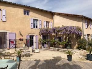 LagnieuGITE DU ROY D'AMONT (Plaine de l'Ain)的紫色门的建筑和鲜花盛开的庭院