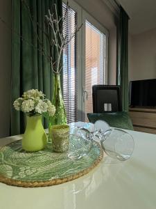 哥鲁拜克Apartmani "MARIJA" Golubac的一张桌子上放着绿花瓶和鲜花