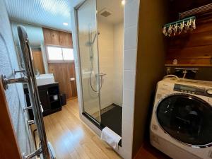 白马村Hakuba Mountain Cabin的一间带洗衣机和玻璃淋浴间的浴室