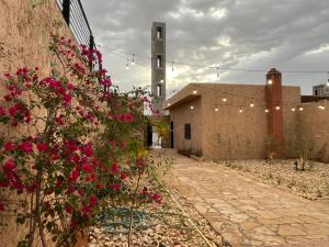 利雅德شاليهات حائط طيني的一座种有粉红色花卉的庭院和一座建筑
