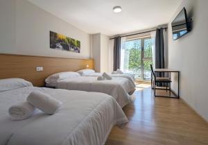 阿尔苏阿Duerming Villa de Arzúa的酒店客房设有三张床和窗户。