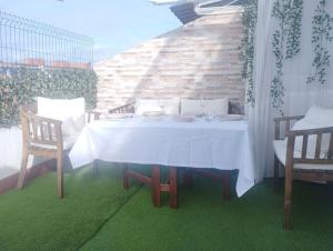 奥维多Ático 4 personas con terraza amueblada y vistas.的庭院内一张带两把椅子的白色桌子