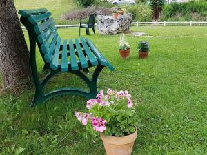 米茹Dvacances Résidence les tavaillons的绿长椅,坐在树和鲜花旁边