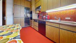 巴塞尔Unique Serviced Living @ Wettstein Turnerstrasse的铺有红色地板并配有木制橱柜的厨房