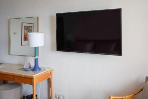 珊瑚湾塞浦路斯珊瑚海滩酒店和度假胜地的墙上的电视机,桌子上有一盏灯