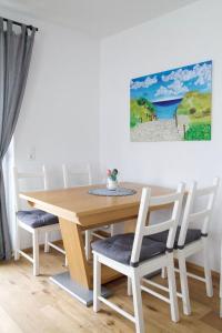萨菲登安斯泰内嫩米尔Appartement HANNE的餐桌和椅子,墙上有绘画作品