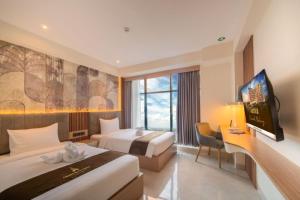 SeturanGrand Altuz Hotel Yogyakarta的酒店客房设有两张床和一台平面电视。