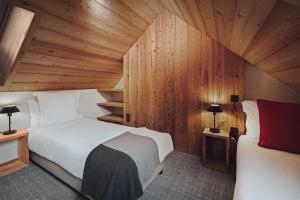 蒙乃第耶-勒潘Alliey & Spa Piscine Appart-hôtel Serre chevalier的一间卧室设有两张床和木墙