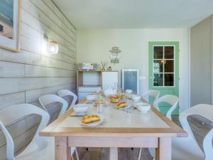 拉卡诺奥肯Holiday Home Domaine Golf Resort-2 by Interhome的一间带木桌和白色椅子的用餐室