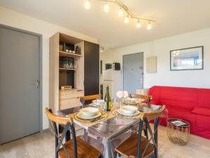 朋泰雷克Apartment Les Balcons de l'Atlantique-12 by Interhome的一间带桌子和红色沙发的用餐室