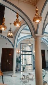 塞维利亚唐佩德罗宫酒店的大楼内带桌子和吊灯的大堂