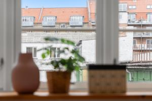 奥尔堡Come Stay - 2BR Det perfekte hjem for 5的坐在窗台上的植物,享有建筑的景色