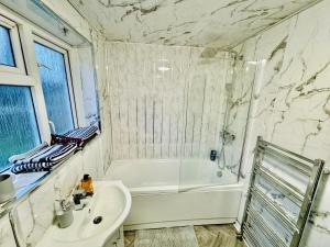 斯托桥4-Bed Full House Stourbridge Birmingham的浴室设有白色浴缸、水槽和浴缸。