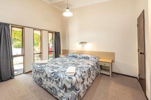 旺格努伊河滨汽车旅馆的一间卧室配有一张床、一张桌子和一个窗户。