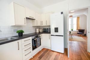 布里斯托St Marks House, Easton, Great Location, Free Parking的厨房配有白色橱柜和白色冰箱。