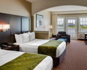 钦科蒂格Comfort Suites Chincoteague Island Bayfront Resort的酒店客房,配有两张床和椅子