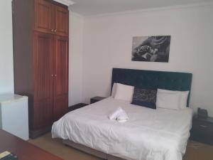 布隆方丹Sapphire Hotel Halevy Heritage的一间卧室配有一张白色床和绿色床头板