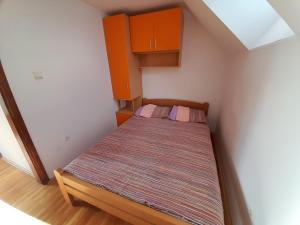 兹拉蒂博尔Apartmani Nova Zova的一张小床,位于一个小房间,配有橙色橱柜