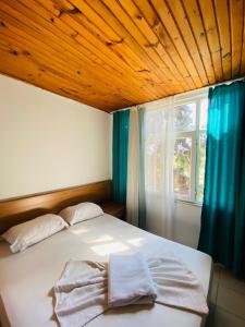 锡德ZÜMRÜT PANSİYON Side的一间卧室设有一张带木制天花板和窗户的床。