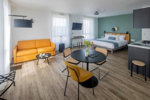 勒阿弗尔All Suites Appart Hotel Le Havre的酒店客房带一张床、一张桌子和椅子