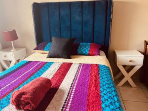 哈拉雷Remarkable 2-Bed Apartment in Harare的一间卧室配有一张带色彩缤纷的毯子和枕头的床。
