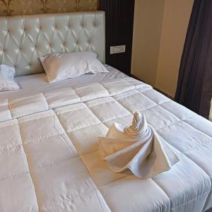 迈索尔HOTEL RAMSON'S INTERNATIONAL的一张白色的床,上面有一条折叠毛巾
