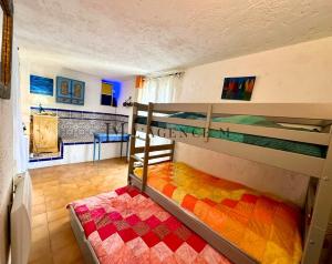 阿尔加约拉Maison de village typique bord de mer的一间卧室配有两张双层床和色彩缤纷的毯子