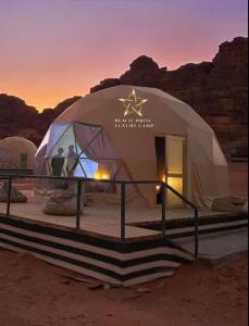 瓦迪拉姆RUM SUNRlSE LUXURY CAMP的日落时在沙漠中的一个大型圆顶帐篷