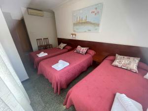萨拉戈萨康伯利旅馆的配有粉红色床单的客房内的三张床